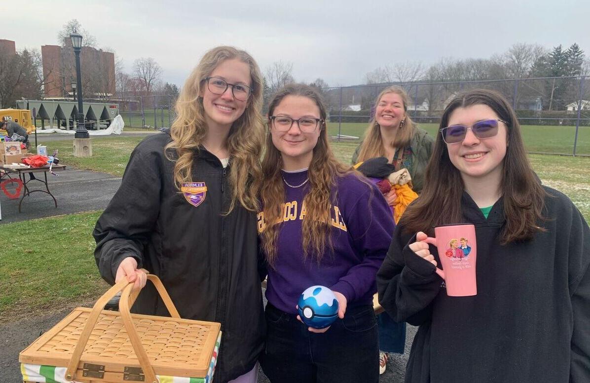 A group of female students pose with upcycled items they found during the Climate Teach-In